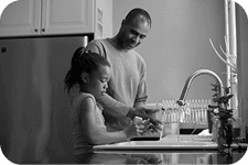 A parent helping a child at the kitchen counter
