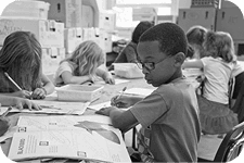 A teacher supervising students working at their desks in a classroom